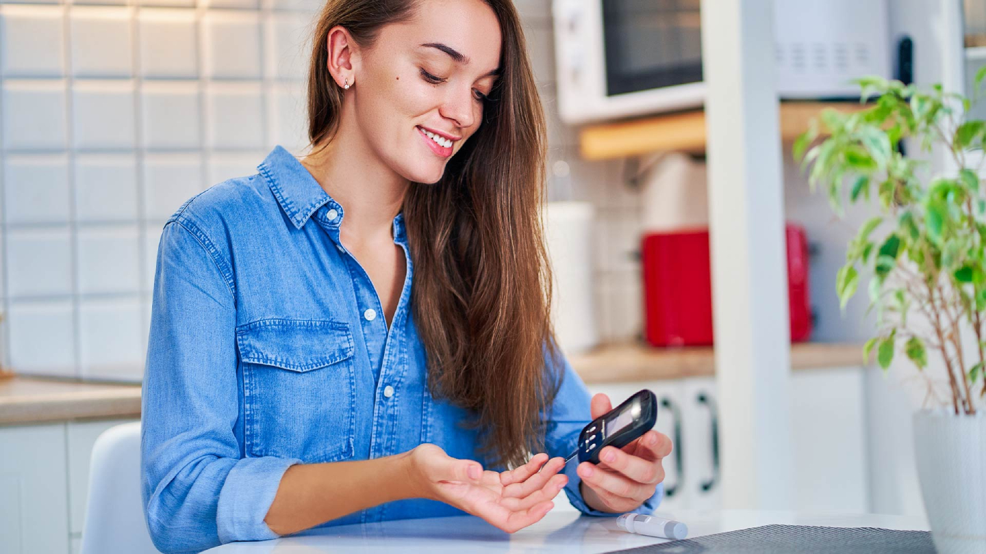 Nasmejana žena meri šećer u krvi glukometrom