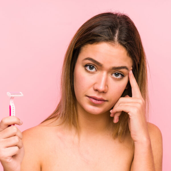 Mlada žena drži brijač i izgleda zabrinuto