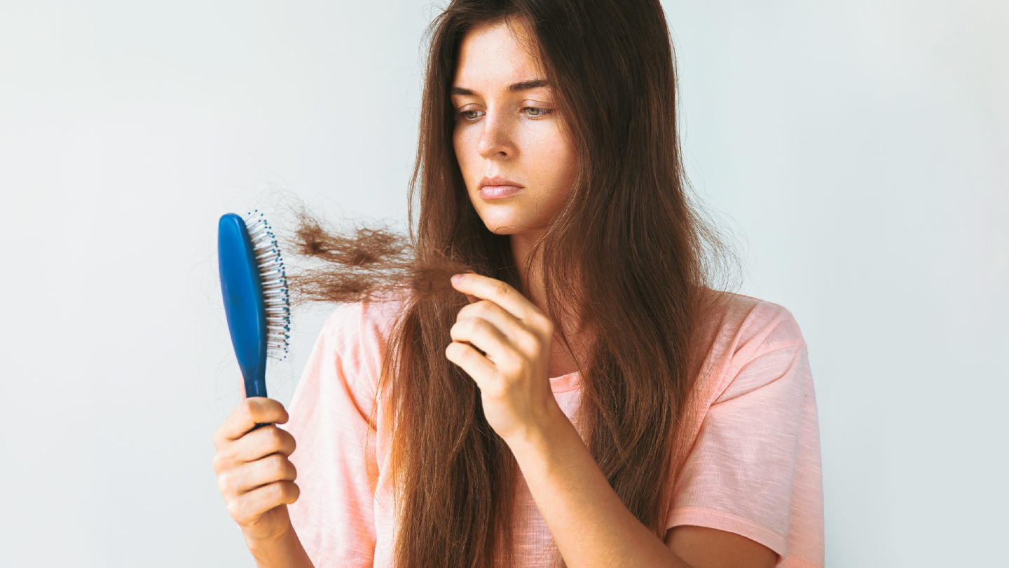 Žena drži četku sa iščupanom kosom zbog gubitka kose